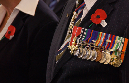 A close up shot of the left side of a persons chest. They are wearing medals on the left, with a poppy above them.
