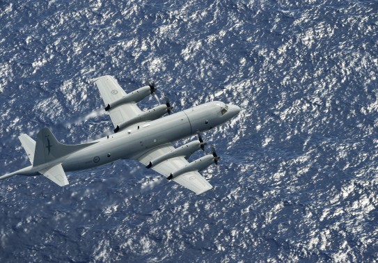 A Royal New Zealand Air Force Orion flies over the blue ocean