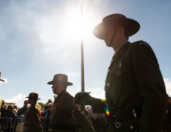 New Zealand Army soldiers as part of a Royal Guard of Honour for Anzac Day 2018. The main focus point is soldier carrying a sword and is backlit with the sun. Other soldiers are shown around and in the background you can see members of the public watching