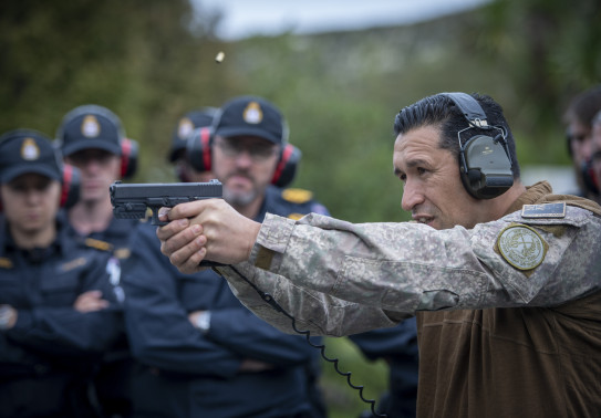 A New Zealand Army soldier fires a Glock G17 Gen 4 with other NZDF personnel watching on in the background. These personnel are out of focus. 