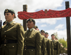 New Zealand Army soldiers walk under an arch made of Māori carvings