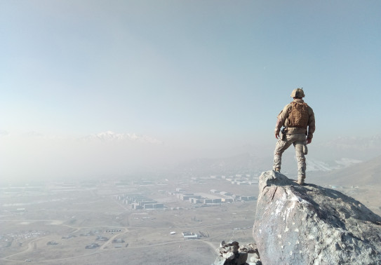 A New Zealand Army solider stands on a rock and looks out over parts of Afghanistan