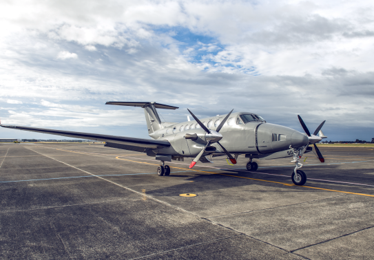 A King Air 350 aircraft sits on the flightline. The sky is cloudy with partial blue sky.