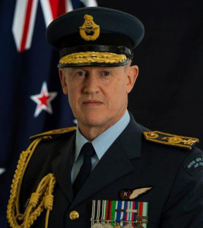 Air Marshal Kevin Short in full dress uniform standing in front of a New Zealand flag, looking to camera.
