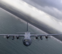 A C-130H(NZ) Hercules banking while flying over ocean.