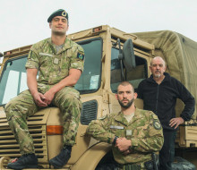 Army personnel pictured standing in front of an Army Unimog, looking at the camera