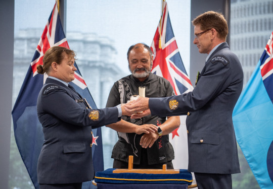 The outgoing Warrant Officer of the Air Force, W/O Toni Tate, hands the Conch, the traditional symbol of the role, to successor W/O Kerry Williams at a ceremony in Defence House this morning. Air Force Tūrangawaewae manager Doug Wallace looks on.