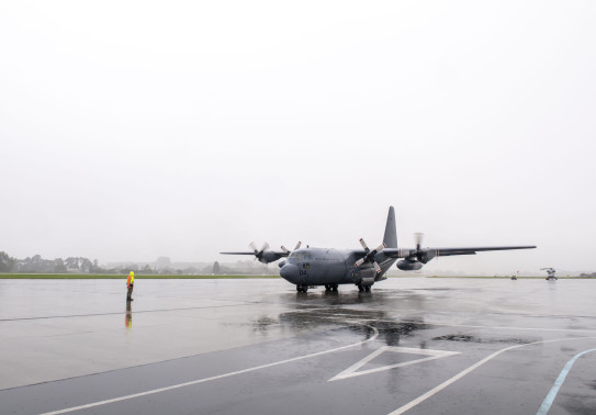 Hercules aircraft on the wet, reflective tarmac of Whenuapai Air Force Base.