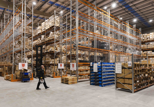 Shelves stocked with goods reach from the floor to the ceiling in a warehouse.