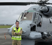 Aviator stands in front of a Seasprite helicopter 