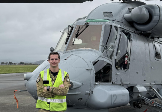 Aviator stands in front of a Seasprite helicopter 