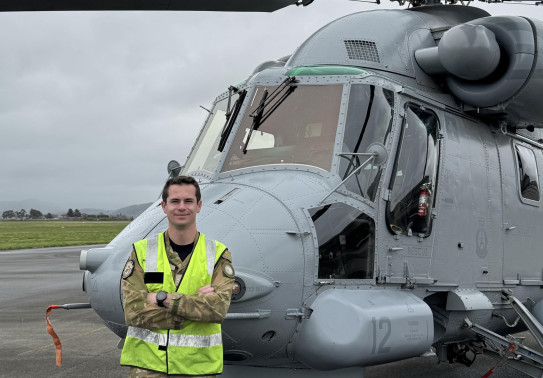 Aviator stands in front of a Seasprite helicopter 