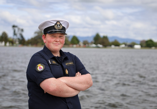 A young man stands with arms crossed while wearing the Navy Cadet uniform.