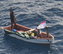 Two people on a small boat who went missing in Kiribati waters waving to camera (on aircraft)  RNZAF P-3K2 Orion following a two-day search.