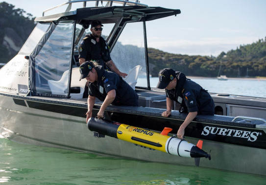 Navy personnel deploy a Remus Autonomous Underwater Vehicle over the side of a Pathfinder aluminium workboat.
