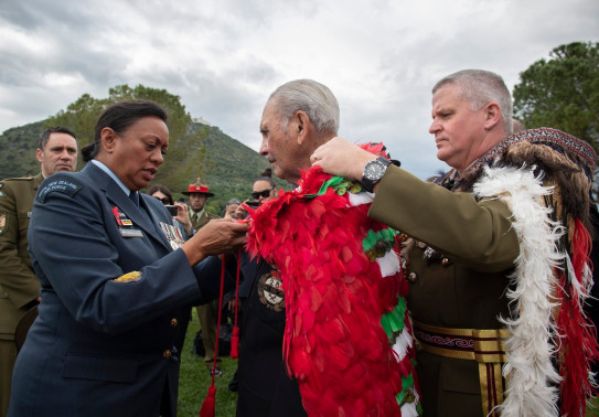 Chief of New Zealand Army Major General John Boswell (right) places our Ngā Tapuwae kahu huruhuru on the last surviving member of B Company, Robert Gillies 2019. A member of the RNZAF assists in the tie on a cloudy day. 