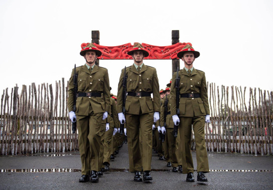 New Zealand Army recruits march in formation through the arch with Māori carvings and onto the parade ground in Waiouru on graduation day