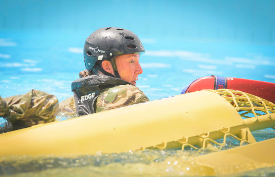 Solders from 3rd Combat Support support battalion swim in a pool, fully uniformed, after escaping the submerged helicopter simulator