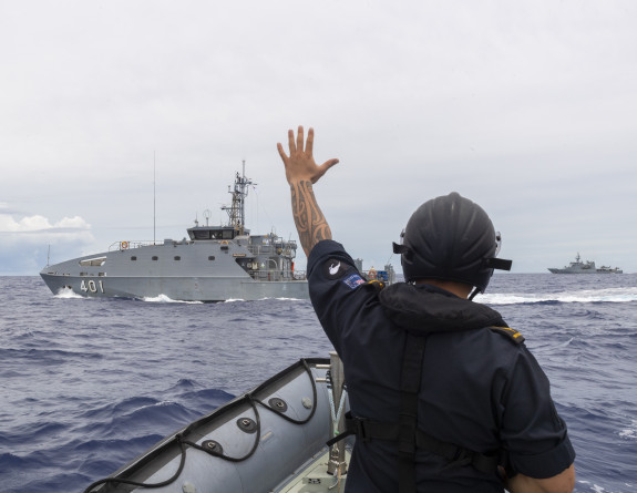 A Royal New Zealand Navy sailor waves to RFNS Savenaca from a Rigid Hulled Inflatable Boatin the background, you can see HMNZS Wellington