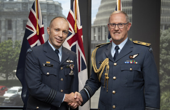 Wing Commander Brett Clayton and the Chief of Defence Force Air Marshal Kevin Short shake hands - in the background three flags