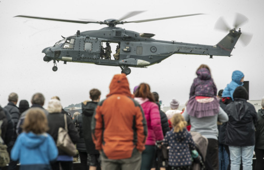 NH90 helicopter conducting a flying display to a crowd of people. 