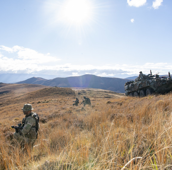 Infantry soldiers and an NZLAV providing security during a combat mission to clear hostile forces from an area