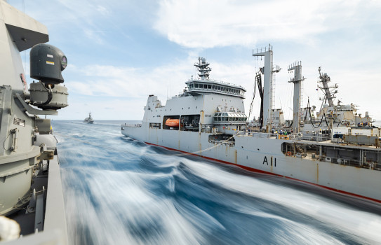 Long exposure photo of HMNZS Aoteaora conducting a replenishment at sea with two other ships.