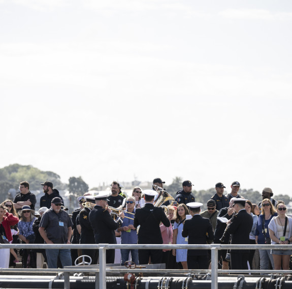 People listen to the Navy band play on the wharf.