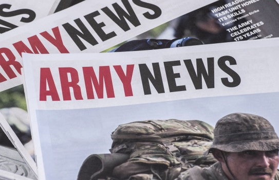 Three editions of Army News stacked a table 