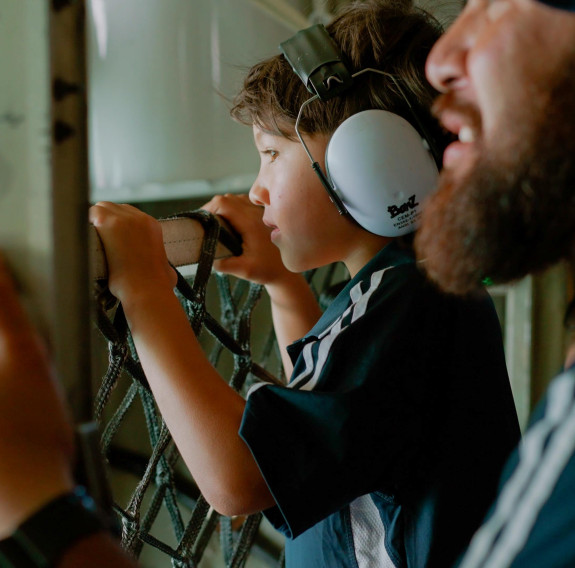 A child and caregiver look over the net out of the back of the Hercules during flight.