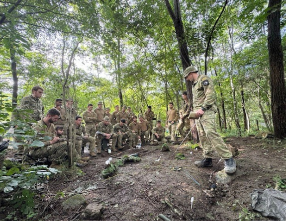 Soldiers conduct a brief in the bush.